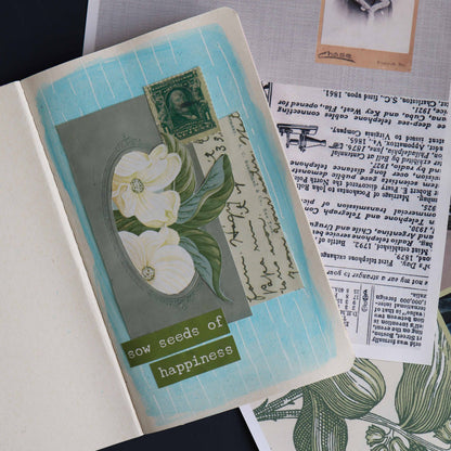 Mixed media art project in a notebook on top of additional sheets of collage paper